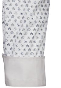 Manica di una camicia bianca in cotone con un piccolo motivo floreale blu e giallo. Presenta una texture in cotone liscia e un polsino semplice di colore chiaro.