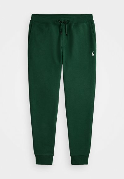Grønne joggebukser laget av mykt stoff, med snor i livet, ribbestrikkede ankler og en liten brodert logo på venstre lår.