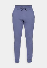 Lila Jogginghosen aus weichem Material, mit einem elastischen Bund, Kordelzugdetails und schmal zulaufenden Beinen mit gerippten Bündchen.