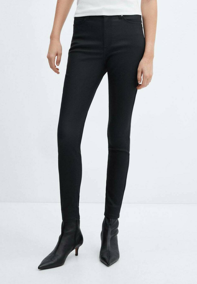 Černé slim-fit džíny s hladkou, elastickou texturou, s mírně zvýšeným pasem a klasickým pětivreckovým střihem, doplněné o špičaté černé podpatky.