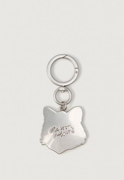 Silver metal keychain shaped like a fox head with "maison kitsuné" engraved in the center, attached to a circular keyring.