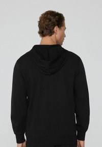 Schwarzer Kapuzenpullover mit langen Ärmeln und verstellbarem Kordelzug. Glattes Material mit lockerer Passform, versehen mit gerippten Bündchen und Saum für zusätzliche Struktur.