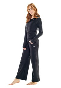 Black long-sleeve top with round neckline, paired with loose black pants featuring side pockets. Soft fabric with a smooth texture.