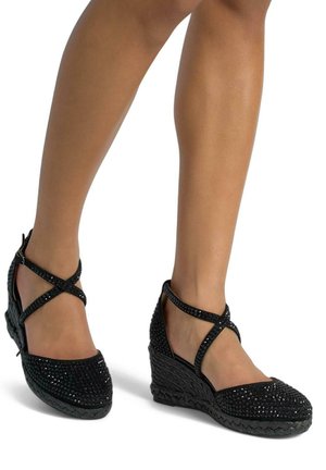 Scarpe con tacco nero con suola intrecciata texturizzata, adornate con dettagli luccicanti e cinturini alla caviglia incrociati per una vestibilità sicura.