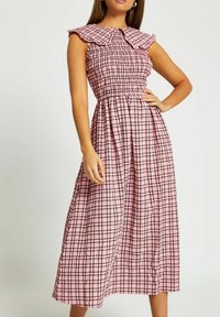 Rosa routad midi-klänning med smockad liv, volangkrage och ärmar i armbågs längd. Har en lätt kjol och rutmönster med svarta accenter.