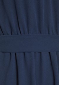 Mörkblå klädfabric med en strukturerad yta, med ett slätt midjeband och veckade detaljer som sträcker sig nedåt.