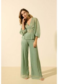 Ensemble deux pièces vert clair comprenant un haut en tulle texturé avec des manches bouffantes et un pantalon à jambes larges au design fluide.