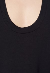 Schwarzes ärmelloses Top mit einem weiten, abgerundeten Ausschnitt. Der Stoff ist glatt mit einer gerippten Textur am Rand des Kragens.