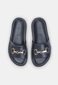 Sandale din piele neagră cu vârful deschis, prezentând o curea lată cu un accent de lanț de culoare aurie. Textură netedă și design minimalist.