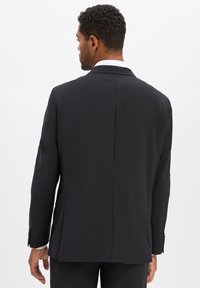 Giacca nera con taglio sartoriale, con spacco singolo sul retro e polsini abbottonati. Tessuto liscio con un design pulito e moderno.