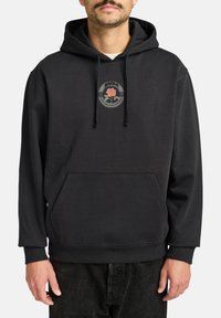 Black hoodie with a front kangaroo pocket, featuring a circular patch with a rose design and text. Made from soft fabric with ribbed cuffs.