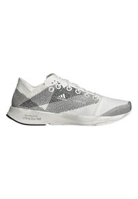 Zapatilla deportiva blanca con parte superior texturizada que presenta un patrón de líneas negras, suela plana y puntera reforzada. La marca es visible en el lateral.