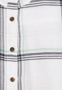 Overhemd met knoopsluiting in een wit en geruit patroon met zwarte, groene en oranje lijnen. Glad, lichtgewicht stof met bruine knopen.