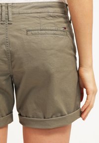 Krótkie spodenki w kolorze khaki z podwiniętym obszyciem, wykonane z gładkiej bawełnianej mieszanki. Posiadają tylną kieszeń z małym logo marki w kolorach czerwonym, białym i niebieskim.