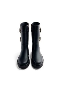 Botas impermeables negras hechas de material sintético liso con puntera redonda, caña alta y detalles en hardware en tono dorado en los laterales.