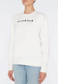 Weißes Sweatshirt mit "mankind" in Schwarz bedruckt. Verfügt über einen Rundhalsausschnitt, lange Ärmel und gerippte Bündchen sowie Saum. Kombiniert mit hellblauen Jeans.