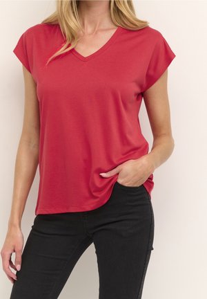 Red v-neck t-shirt with short sleeves, made of soft fabric, featuring a relaxed fit and a rounded hem, paired with black jeans.