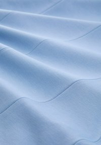 Lichtblauwe stof met een gladde, gestructureerde oppervlakte en subtiele golvende patronen. Zacht afwerking. Ideaal voor verschillende textieltoepassingen.