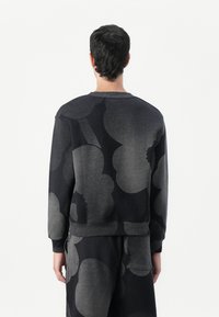Schwarzer Sweatshirt mit großem abstraktem grauen Blumenmuster, Rundhalsausschnitt und gerippten Bündchen. Der Stoff wirkt weich mit einer strukturierten Oberfläche.