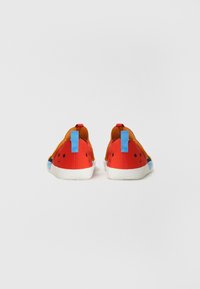 Chaussures slip-on rouges et orange avec une finition lisse, dotées d'accents bleu clair, de trous de ventilation et d'une semelle blanche.