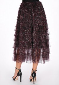 Fustă din tull cu imprimeu leopard de culoare neagră și burgundă, cu straturi transparente, până la genunchi, asortată cu pantofi cu toc înalt negri.