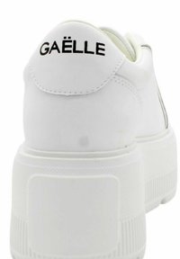 Białe skórzane sneakersy z zaokrąglonym tyłem, podwyższoną piętą i czarnym logo "GAËLLE". Posiadają teksturowaną podeszwę dla lepszej przyczepności oraz wyściełany kołnierz.