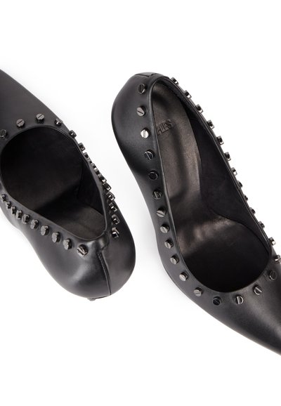 Sorte skinnpumps med rund tå, utskårne detaljer og nagledekanser langs kantene. Glatt tekstur med matt finish.