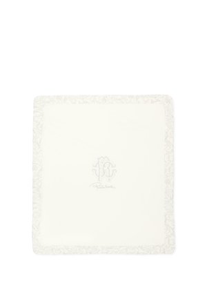 Panno quadrato color crema con bordo floreale decorativo e sottile logo e firma ricamati al centro.