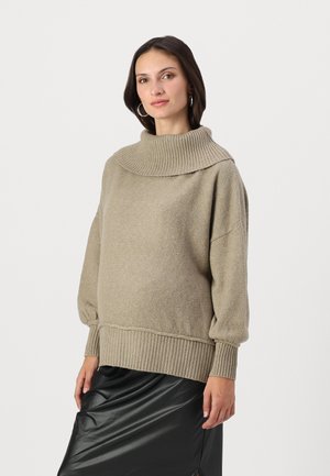 Knit sweater in soft beige with a high, ribbed collar, dropped shoulders, and ribbed cuffs and hem. Paired with a black, shiny skirt.