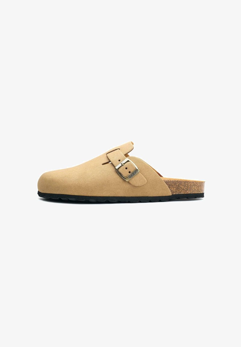 Beige suede clog with a rounded toe, adjustable metal buckle, cork footbed, and black rubber outsole. No heel.