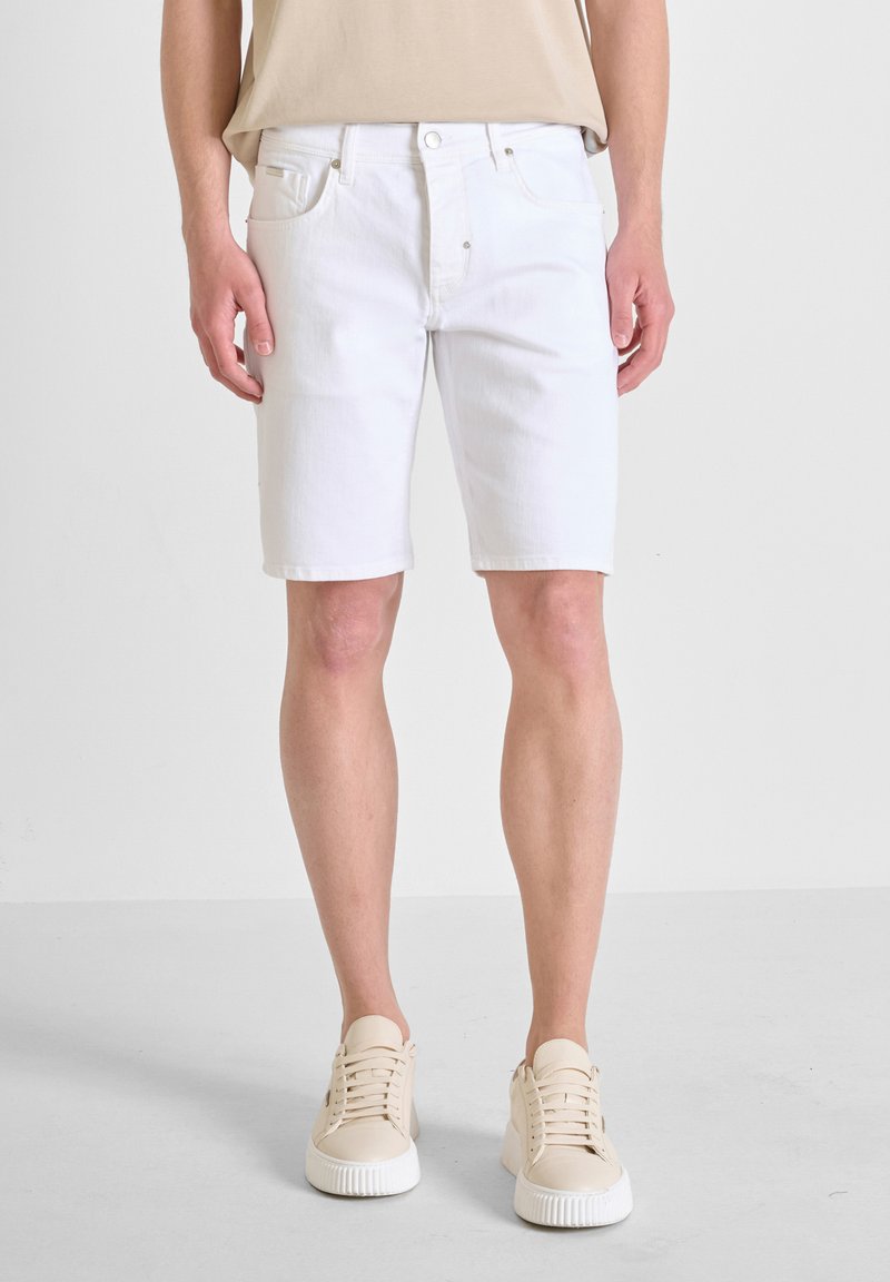 Witte denim shorts met een klassiek vijf-pocket ontwerp, voorzien van een rits en subtiele stiksels, gecombineerd met beige sneakers.