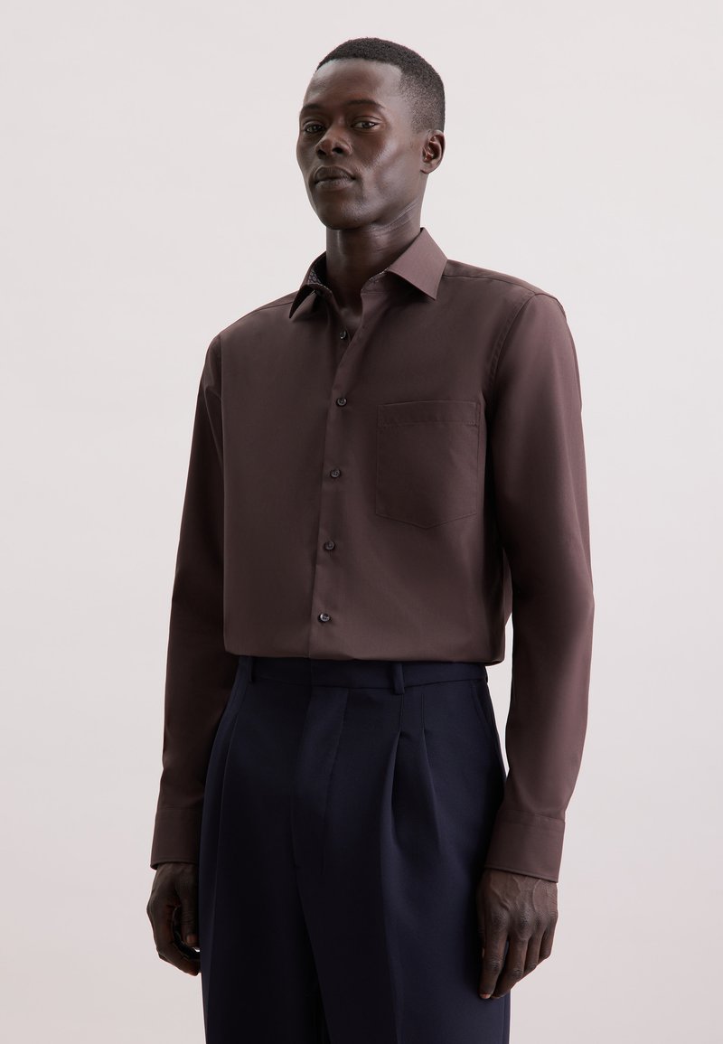Bruine lange mouwen shirt in gladde stof met een button-down kraag, voorzien van een borstzak en donkere knopen, gecombineerd met marineblauwe broek.