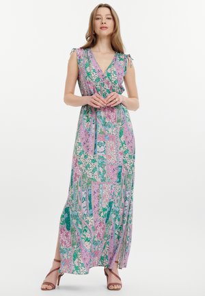 Maxi jurk in een bloemenpatchworkpatroon met tinten groen, roze en blauw; heeft een V-hals, strikbandjes en zijsplitten.