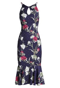 Abito floreale aderente in blu navy con pois. Presenta un collo a fessura, spalline sottili e un orlo ampio. Il motivo floreale include fiori rosa e bianchi.