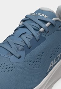 Μπλε αθλητικό παπούτσι με επάνω μέρος από δίχτυ, λεπτομερές κορδόνι, οπές για διαπνοή και λευκή σόλα με το όνομα της μάρκας στο πλάι.