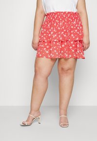 Red floral print layered mini skirt with a stretchy waistband. Lightweight, sheer fabric with small white flowers and a flowing design.