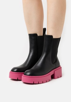 Czarne skórzane botki za kostkę z grubą różową gumową podeszwą, z elastycznymi bocznymi panelami i gładkim wykończeniem, zaprojektowane z myślą o łatwym zakładaniu.