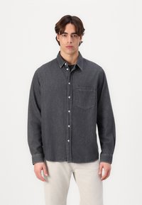 Dunkelgrau denimhemd mit Button-Down-Kragen, langen Ärmeln und einer einzelnen Brusttasche. Hat sichtbare Nähte und einen lässigen Schnitt.
