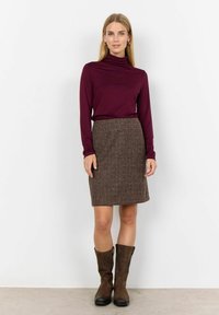 Bordeaux langærmet top parret med en brun struktureret nederdel og brune knæhøje støvler. Outfittet har et tætsiddende design og lag-på-lag look.