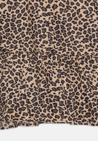 Tessuto maculato leopardato in beige con macchie marroni scure, caratterizzato da dettagli plissettati all'orlo. Texture morbida con un aspetto leggero.