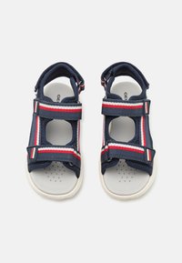 Navy blue toddler sandals with a breathable mesh upper, adjustable hook-and-loop straps, and red and white striped accents.