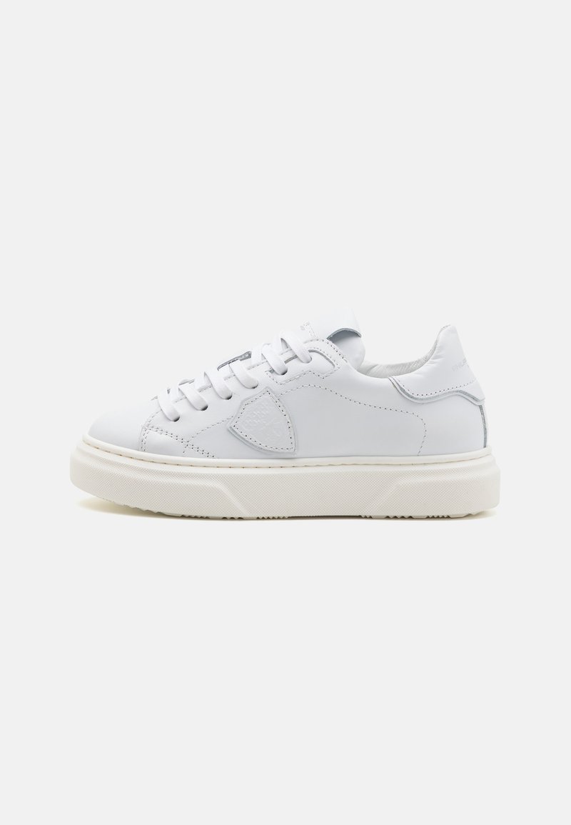 Baskets blanches en cuir avec une surface texturée, un avant à lacets, un col rembourré et une semelle en caoutchouc épaisse et texturée de couleur blanc cassé.