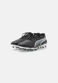 Scarpe da calcio nere con tomaia testurizzata, dettagli bianchi e un pannello in rete. Presentano lacci e una suola borchiata bianca e marrone.
