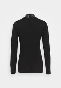 Svart långärmad tröja med hög hals som har en dragkedja och nitar vid kragen, tillverkad av ett mjukt tyg.