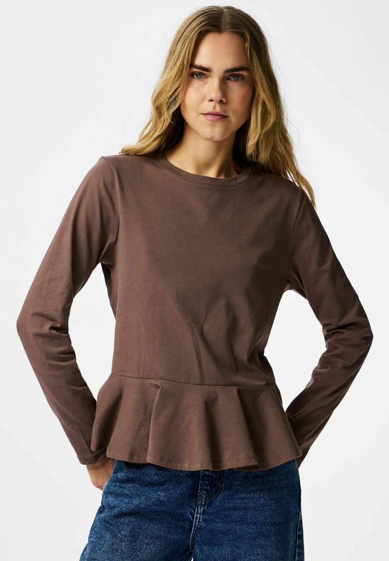 Brun langermet topp med rund hals og peplumkant, laget av mykt stoff, kombinert med blå denimjeans. Enkel og tettsittende design.