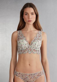 Bloemenkant bralette met een diepe V-hals, golvende randen en een doorzichtige bloemenpatroon in pastelkleuren. Gecombineerd met bijpassende kanten slipjes.