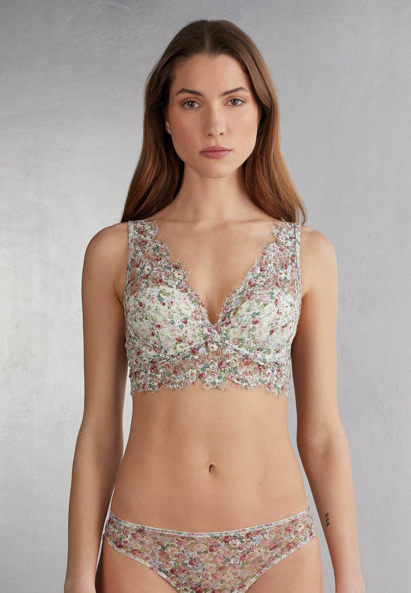 Bloemenkant bralette met een diepe V-hals, golvende randen en een doorzichtige bloemenpatroon in pastelkleuren. Gecombineerd met bijpassende kanten slipjes.