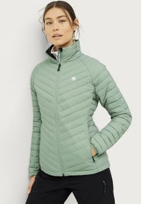 Chaqueta de plumas verde claro con diseño de acolchado diagonal, cuello alto, cierre frontal de cremallera y bolsillos laterales. El material parece suave y aislante.