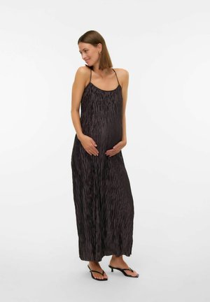 Robe maxi noire plissée avec bretelles fines, coupe ample et texture douce ; associée à des tongs noires, modèle tenant son ventre sur un fond neutre.