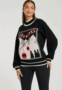 Zwart gebreid sweater met witte en rode accenten, voorzien van een bergafbeelding, kabelbanen en de tekst "LES ALPES". Ontspannen pasvorm en geribde manchetten.